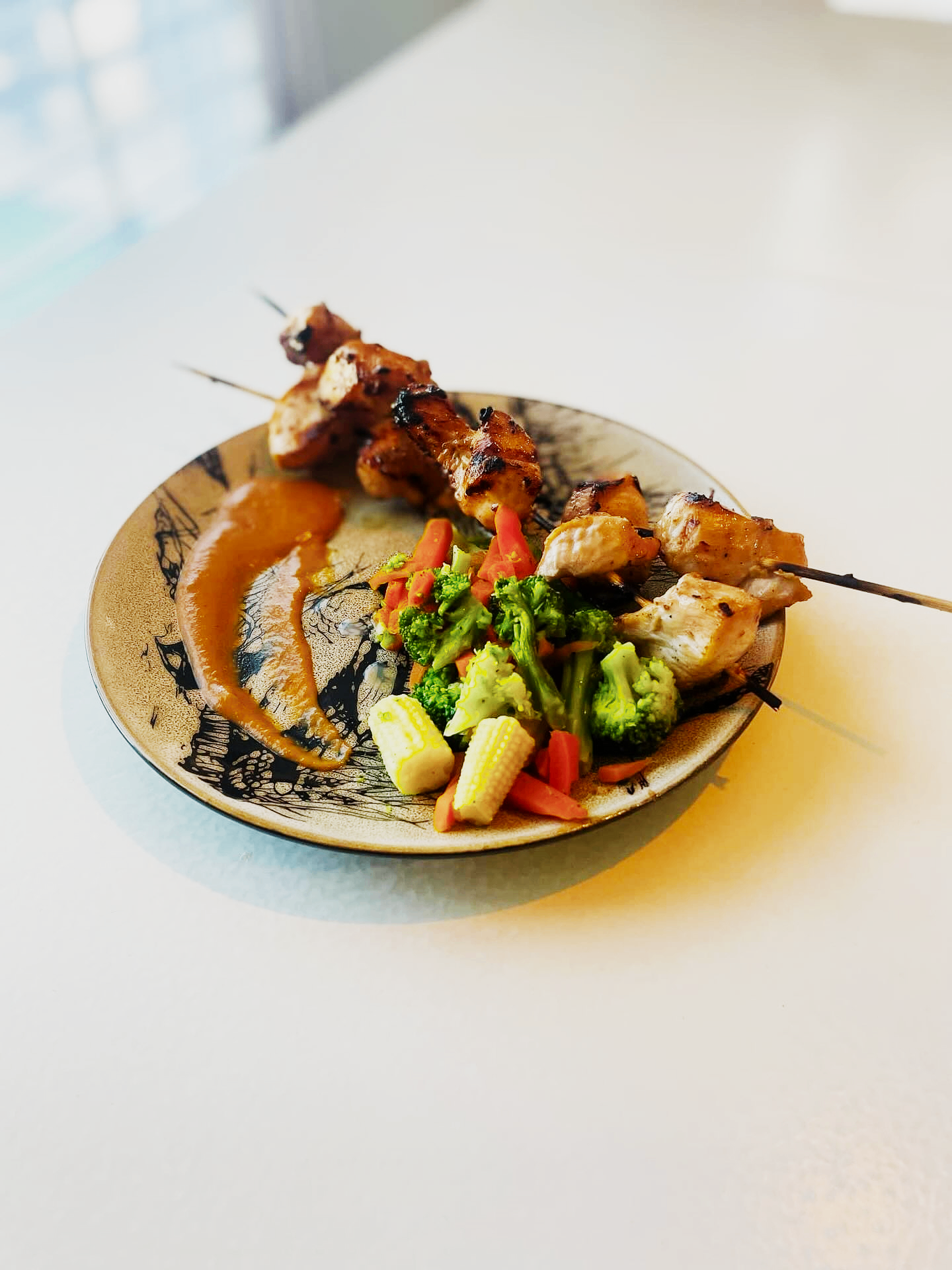 Plated chicken skewers with vegetables and sauce